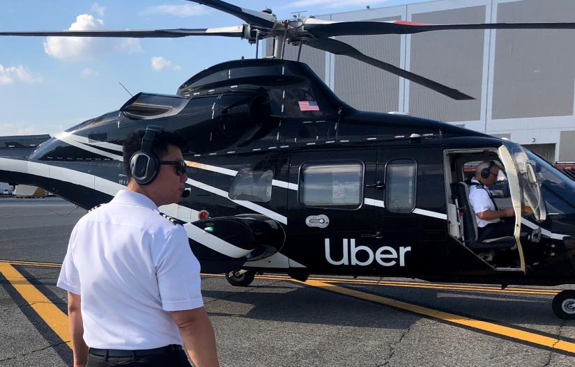 A pilot walks media members towards a waiting helicopter operated by Uber Copter, a new service by the ride-sharing company Uber, providing service from Manhattan to New York`s JFK International Airport initially for Diamond and Platinum Uber Rewards members as well as special Uber partners in New York, U.S., October 2, 2019. Picture taken October 2, 2019. REUTERS