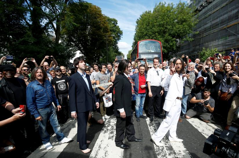 FILE PHOTO: People take pictures as the Beatles cover band members walk on the zebra crossing on Abbey Road in London, Britain August 8, 2019. REUTERS