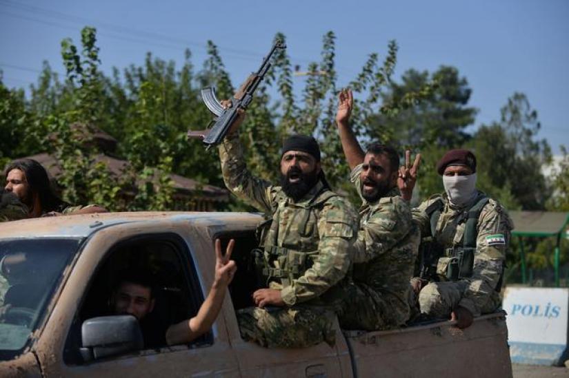 Members of Syrian National Army, known as Free Syrian Army, wave as they drive to cross into Syria near the Turkish border town of Ceylanpinar in Sanliurfa province, Turkey, Oct 10, 2019. REUTERS