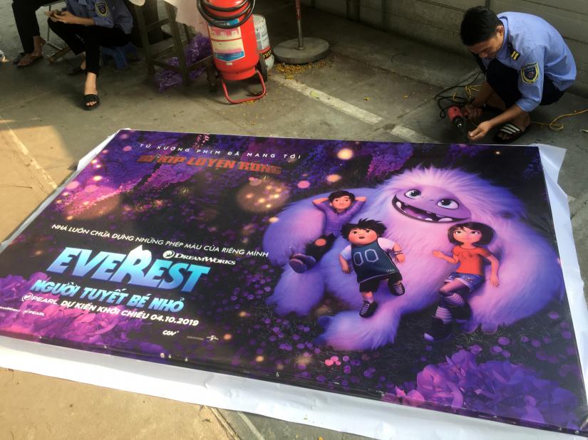 A man takes down a promotional poster for the DreamWorks film `Abonimable` which was being marketed in Vietnam as `Everest: The Little Yeti` at a cinema in Hanoi, Vietnam October 14, 2019. REUTERS