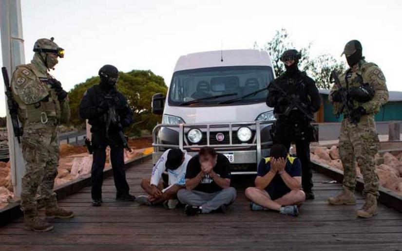 Police officers stand around suspects arrested during an operation that, according to police, resulted in the seizure of 1.2 tonnes of methamphetamine in Geraldton, Australia, December 21, 2017. Picture taken December 21, 2017. Australian Federal Police/Handout via REUTERS