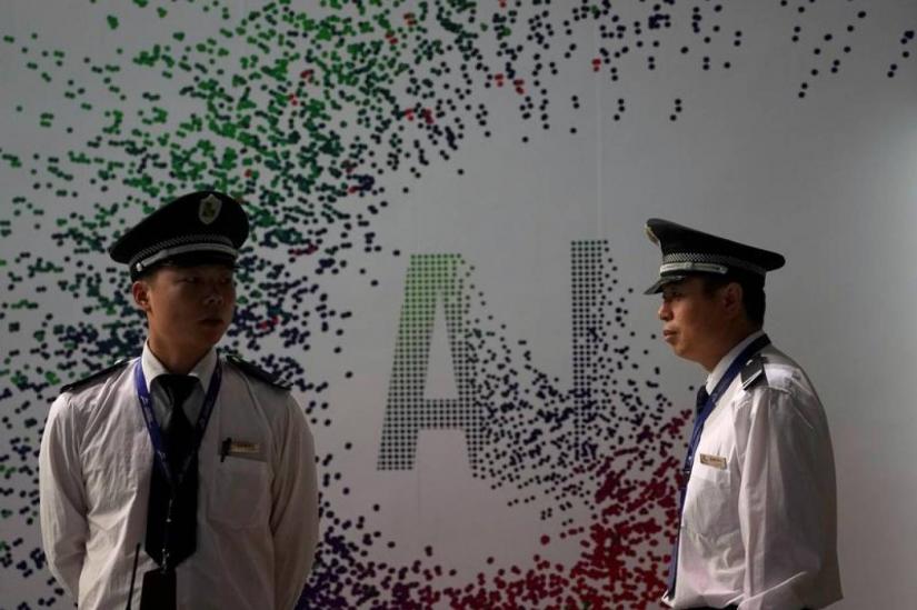 Security officers keep watch in front of an AI (Artificial Intelligence) sign at the annual Huawei Connect event in Shanghai, China September 18, 2019. REUTERS