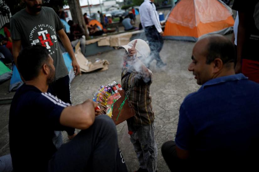 FILE PHOTO: A boy selling candies and cigarettes gestures to the camera as he argues with migrants from India outside of Siglo XXI migration facility in Tapachula, Mexico, May 13, 2019. REUTERS