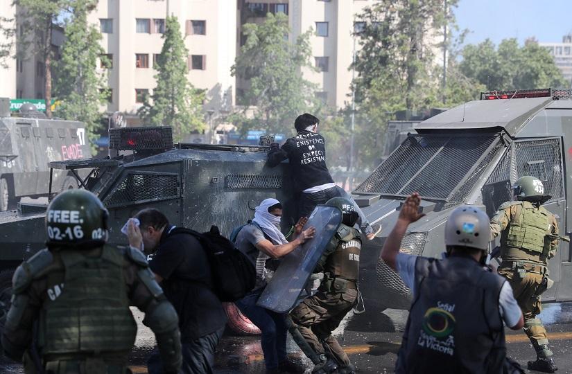 Protesters clash with riot police officers during a protest against Chile`s state economic model in Santiago, Chile Oct 20, 2019. REUTERS