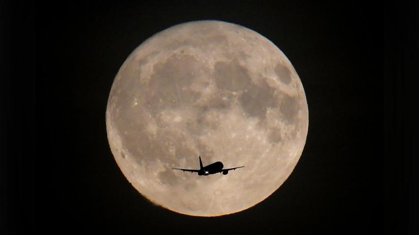 FILE PHOTO: A passenger plane is seen with the full moon behind as it begins its final landing approach to Heathrow Airport in London, Britain, Sept 24, 2018. REUTERS
