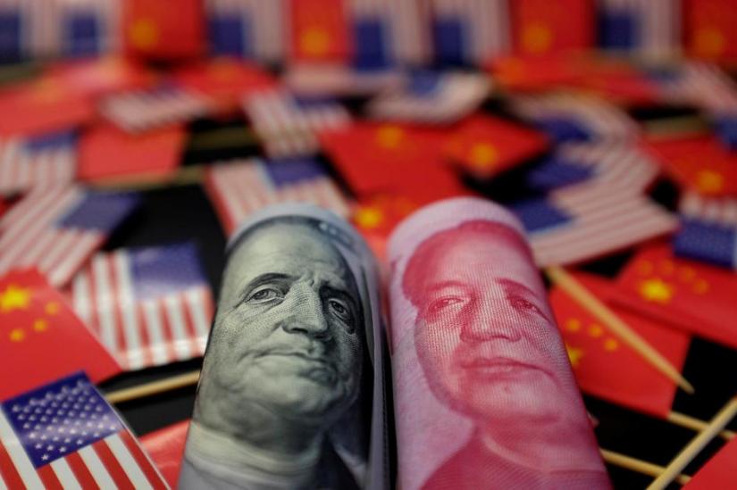 FILE PHOTO: A US dollar banknote featuring American founding father Benjamin Franklin and a China`s yuan banknote featuring late Chinese chairman Mao Zedong are seen among US and Chinese flags in this illustration picture taken May 20, 2019. REUTERS/Illustration