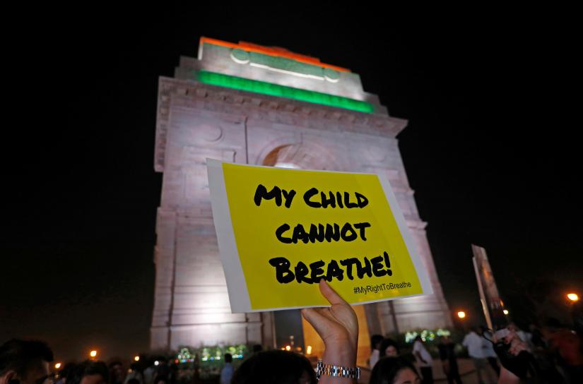 A protestor holds a placard in front of the India Gate during a protest demanding government to take immediate steps to control air pollution in New Delhi, India, November 5, 2019. REUTERS