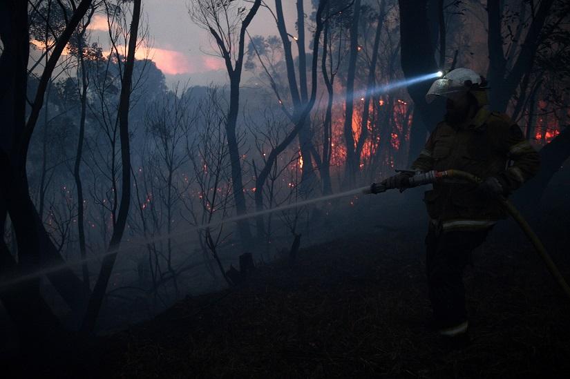 A NSW Rural Fire Service firefighter conducts property protection as a bushfire burns close to homes on Railway Parade in Woodford NSW, Australia, Nov 8, 2019. AAP Image/REUTERS