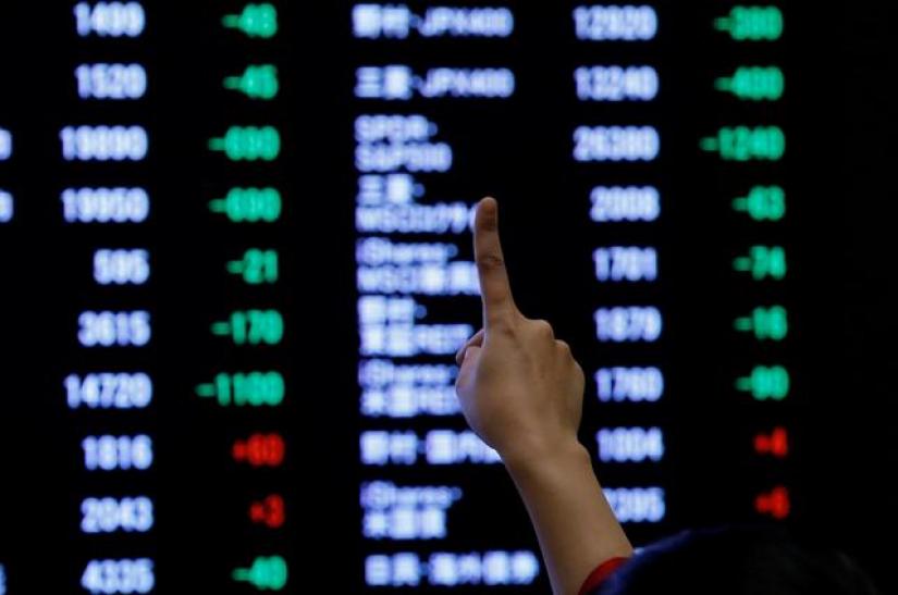FILE PHOTO: A woman points to an electronic board showing stock prices at the Tokyo Stock Exchange (TSE) in Tokyo, Japan, January 4, 2019. REUTERS