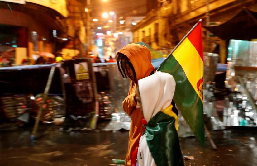 People walk past a barricade during a protest against Bolivia`s President Evo Morales in La Paz, Bolivia November 10, 2019. REUTERS