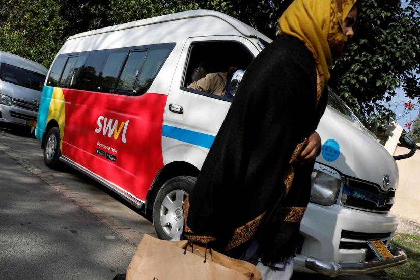 A woman walks past a vehicle with a logo of the Egyptian transport technology start-up Swvl, parked along a road in Islamabad, Pakistan, Nov 11, 2019. REUTERS