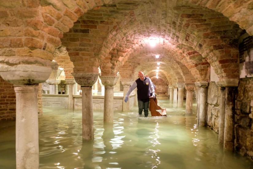 FILE PHOTO: A man wades in the flooded crypt of St Mark`s Basilica during a period of exceptionally high water levels in Venice, Italy Nov 13, 2019. REUTERS