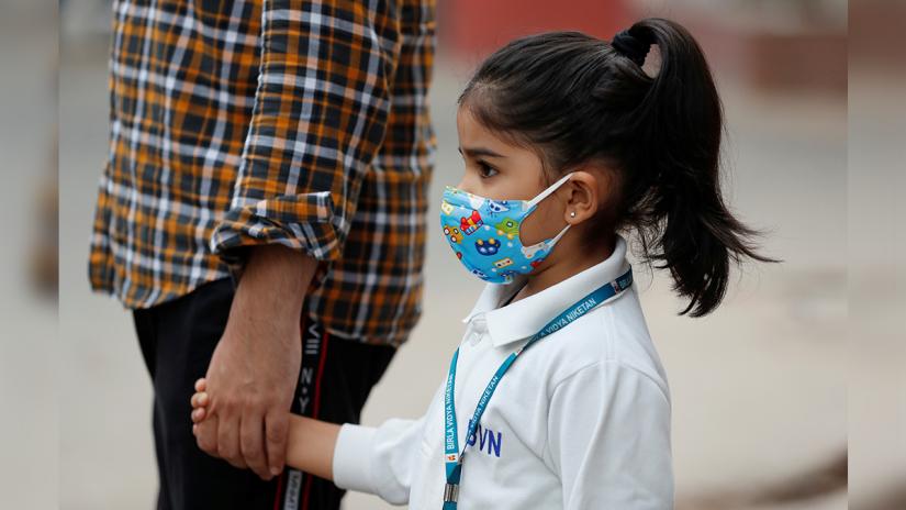 A schoolgirl wearing a protective mask holds her father`s hand as she waits for her school bus on a smoggy morning in New Delhi; Photo: Reuters