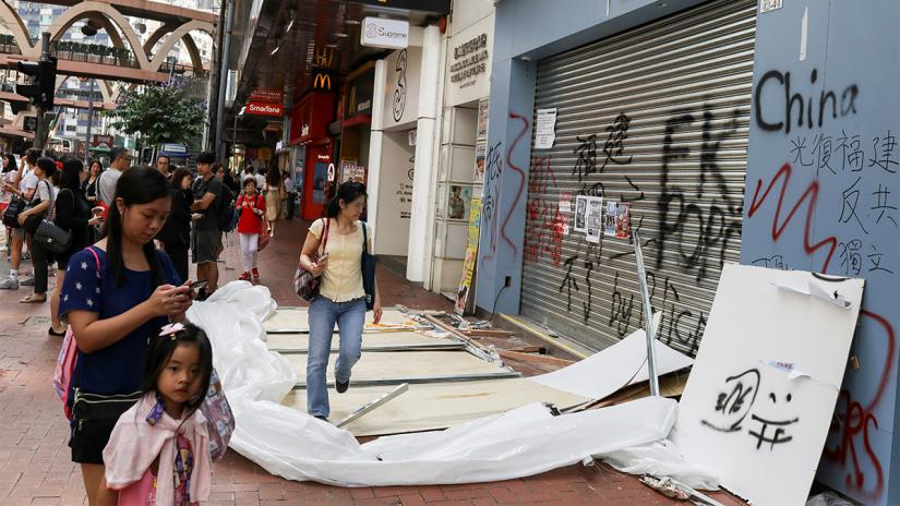 People walk past a vandalised store during Anti-Extradition movement in Hong Kong