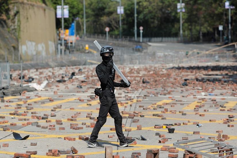 An anti-government protester walks on a road scattered with bricks outside the Polytechnic University in Hong Kong, China, Nov 16, 2019. REUTERS
