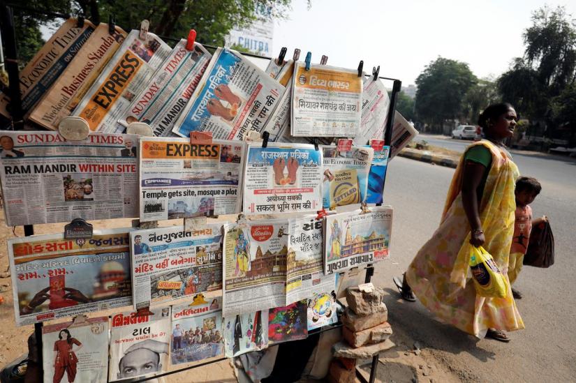 A woman with her son walks past newspapers hanging at a stall with the headlines about Supreme Court`s verdict on a disputed religious site in Ayodhya, in Ahmedabad, Nov 10, 2019. REUTERS