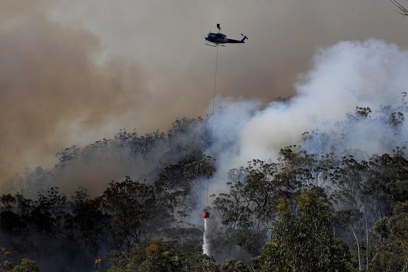 A helicopter drops water to protect property on Wheelbarrow Ridge at Colo Heights, north west of Sydney, Tuesday, Nov 19, 2019. AAP Image/Dan Himbrechts/via REUTERS