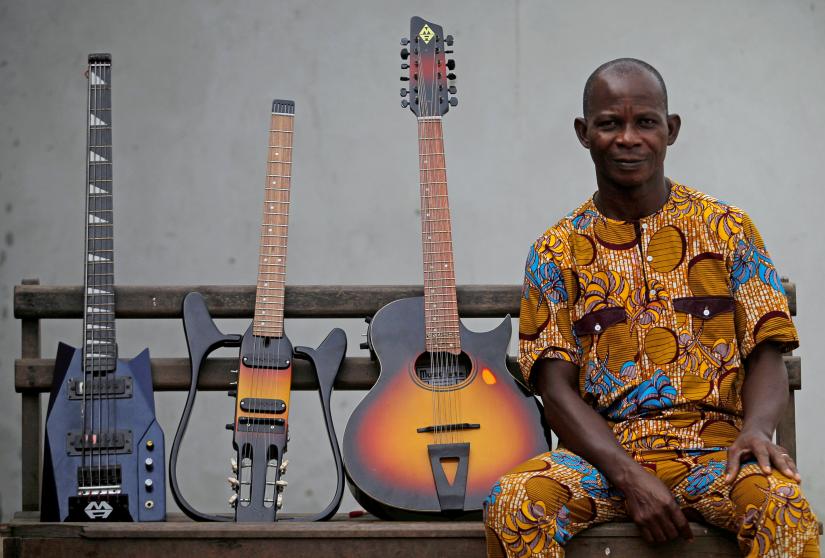 FILE PHOTO: Adicko Pierre, an Ivorian luthier sits next to guitars manufactured by him at his workshop in Abobo, an area of Abidjan, Ivory Coast April 5, 2018. REUTERS
