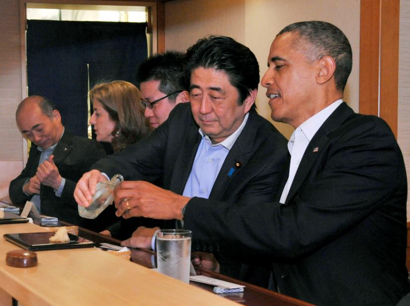 FILE PHOTO : Japanese Prime Minister Shinzo Abe pours sake for U.S. President Barack Obama as they have dinner at the Sukiyabashi Jiro sushi restaurant in Tokyo, in this picture taken April 23, 2014, and released by Japan`s Cabinet Public Relations Office. Cabinet Public Relations Office/Handout via Reuters/File Photo
