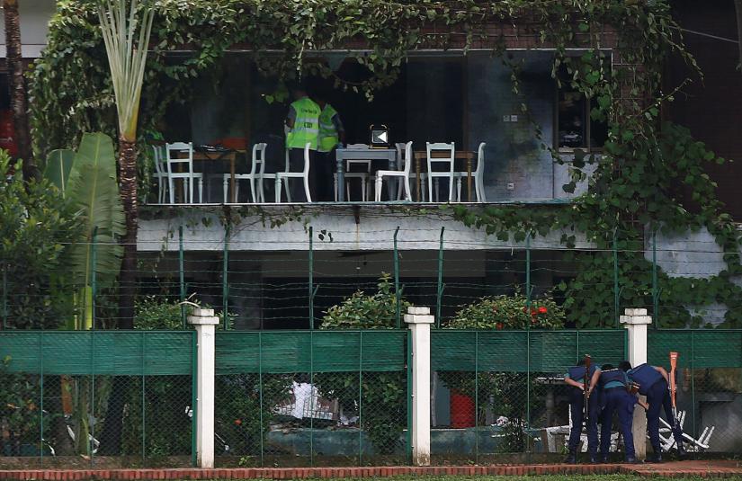 Policemen sneak a look inside the Holey Artisan Bakery and the O`Kitchen Restaurant as others inspect the site after gunmen attacked, in Dhaka, Bangladesh, July 3, 2016. REUTERS/File Photo