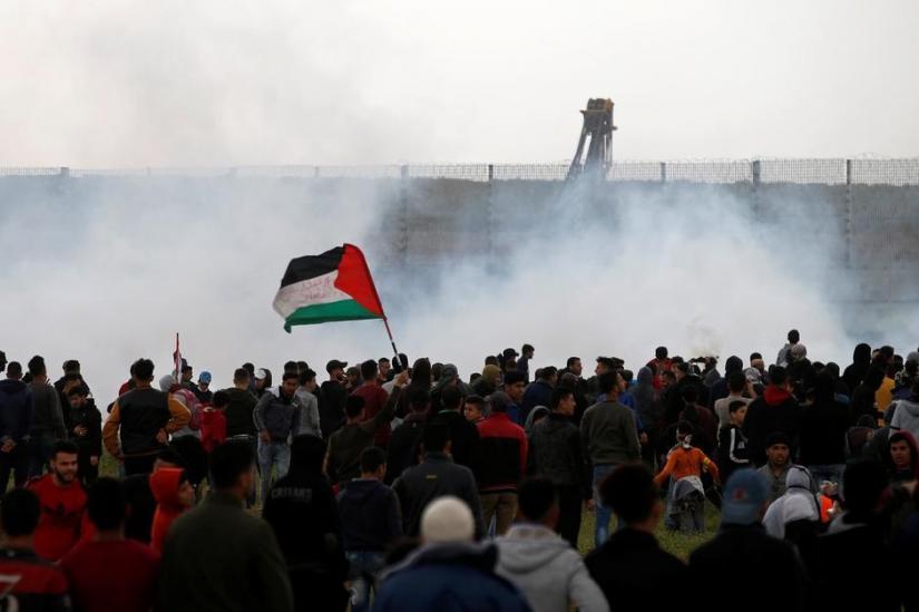 FILE PHOTO: Palestinians gather as tear gas is fired by Israeli forces during a protest marking Land Day and the first anniversary of a surge of border protests, at the Israel-Gaza border fence east of Gaza City Mar 30, 2019. REUTERS