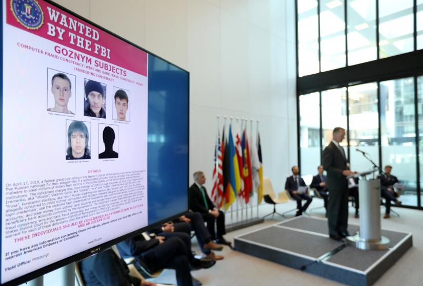 Suspects of cybercrime are seen on the screen at the news conference to announce a major law enforcement action against a transnational organised cybercrime at the Europol`s headquarters in The Hague, Netherlands, May 16, 2019. REUTERS