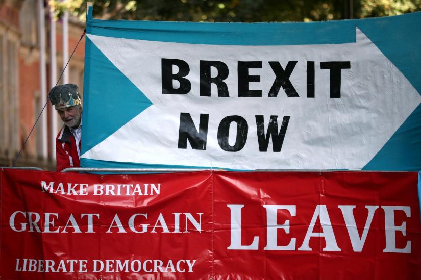 FILE PHOTO: A crown-wearing pro-Brexit demonstrator stands next to banners outside the Supreme Court of the United Kingdom, in London, Britain September 18, 2019. REUTERS