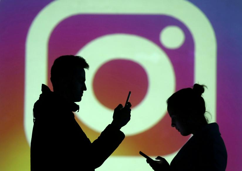FILE PHOTO: Silhouettes of mobile users are seen next to a screen projection of Instagram logo in this picture illustration taken March 28, 2018. REUTERS