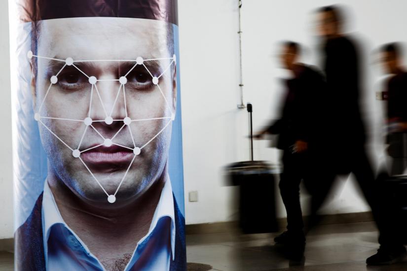 People walk past a poster simulating facial recognition software at the Security China 2018 exhibition on public safety and security in Beijing, China October 24, 2018. REUTERS/File Photo