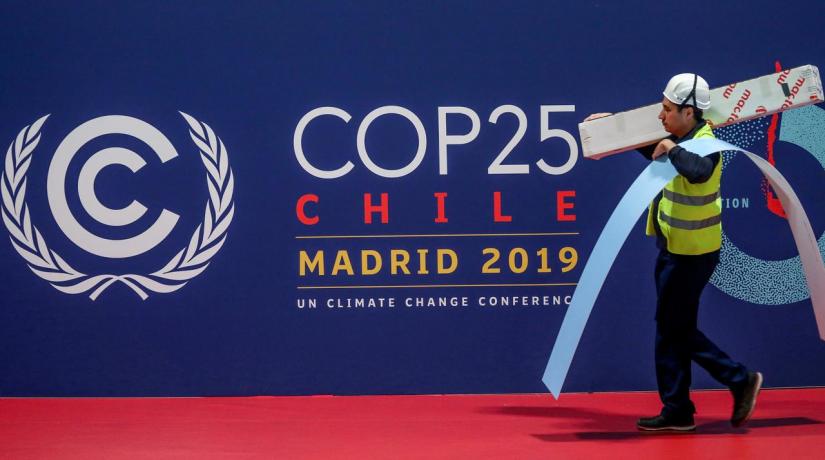 A worker walks past a COP 25 logo at IFEMA Convention Center, ahead of the 2019 UN climate change conference (COP 25) in Madrid, Spain, Nov 30, 2019. REUTERS
