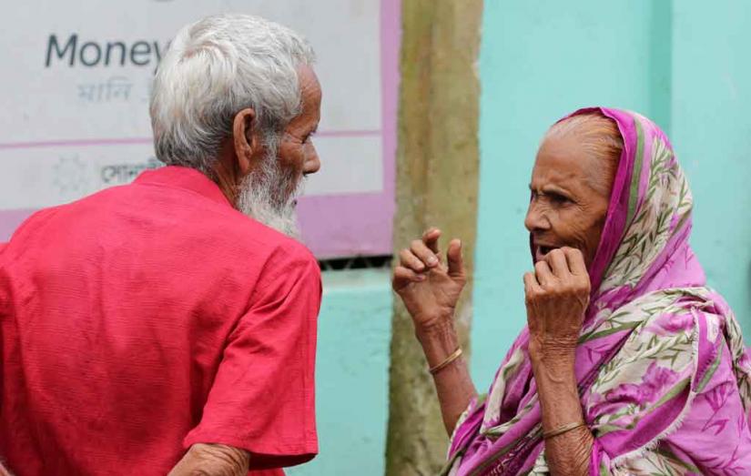 The Sept 2019 photo shows a elderly man and a woman waiting patiently to collect their monthly old age allowance in the northern part of Bangladesh Syed Zakir Hossain/File Photo
