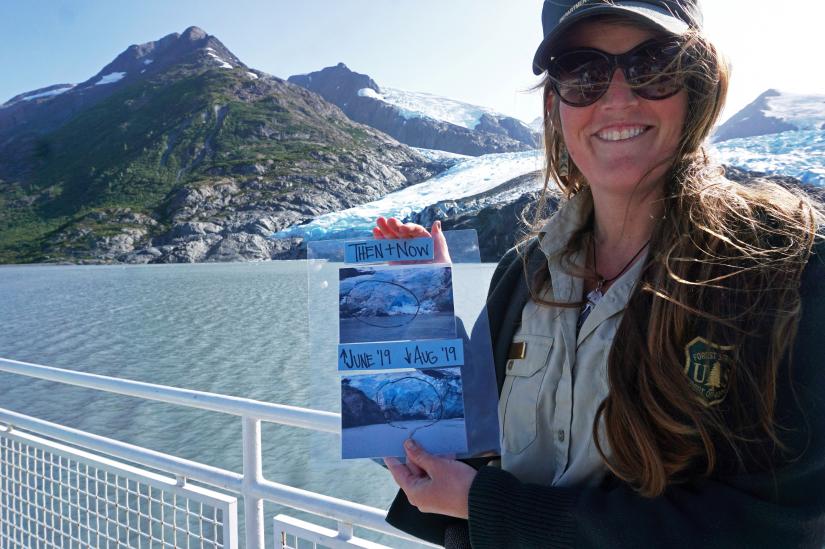 Chugach National Forest ranger Megan Parsley holds photos showing this summer`s ice loss at the face of Portage Glacier, Alaska, U.S. August 17, 2019. Picture taken August 17, 2019. REUTERS