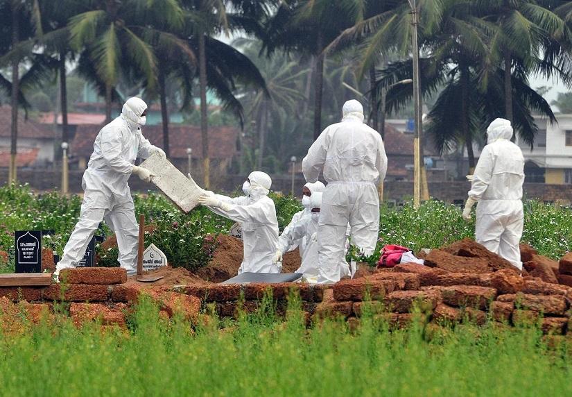 Doctors and relatives wearing protective gear dig a grave to bury the body of a victim, who lost his battle against the brain-damaging Nipah virus, during his funeral at a burial ground in Kozhikode, in the southern Indian state of Kerala, May 24, 2018. REUTERS/File Photo