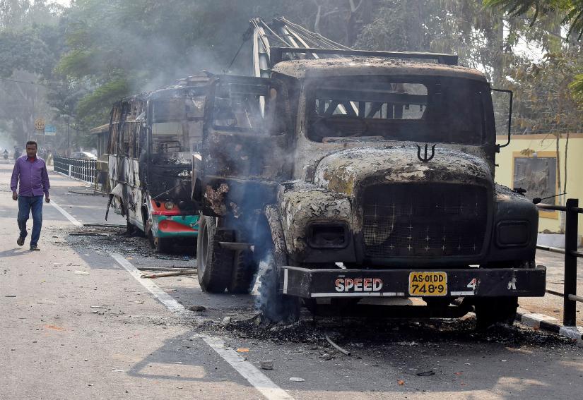 A man walks past damaged vehicles that were set on fire by demonstrators, during a protest after India`s parliament passed Citizenship Amendment Bill, in Guwahati, India December 12, 2019. REUTERS