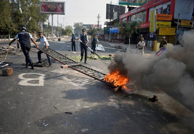 Police remove a burning barricade that was set on fire by demonstrators during a protest after India parliament passed a Citizenship Amendment Bill, in Guwahati, India, December 12, 2019. REUTERS