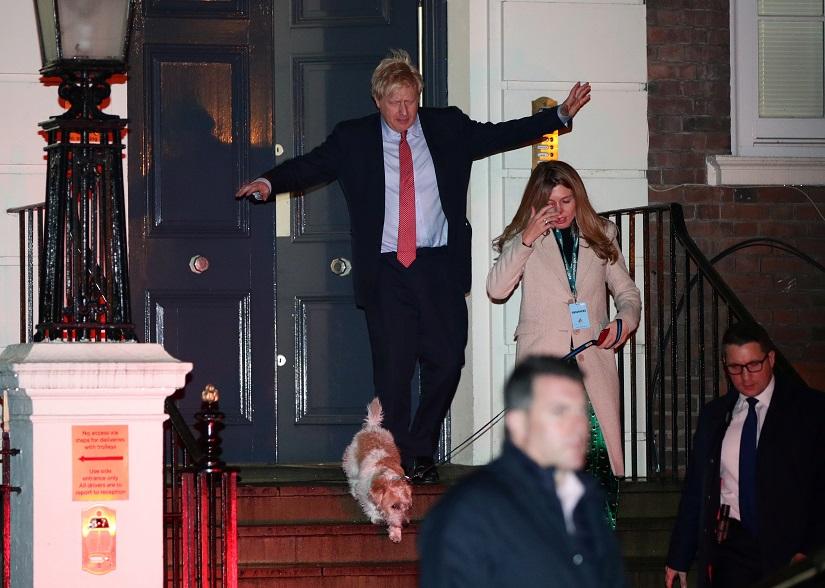 Britain`s Prime Minister Boris Johnson and his girlfriend Carrie Symonds leave the Conservative Party`s headquarters with their dog Dilyn following the general election in London, Britain Dec 13, 2019. REUTERS