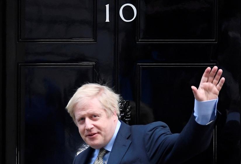Britain`s Prime Minister Boris Johnson waves as he arrives at Downing Street after meeting with the Queen at the Buckingham Palace to ask for permission to form a government, in London, Britain, December 13, 2019. REUTERS
