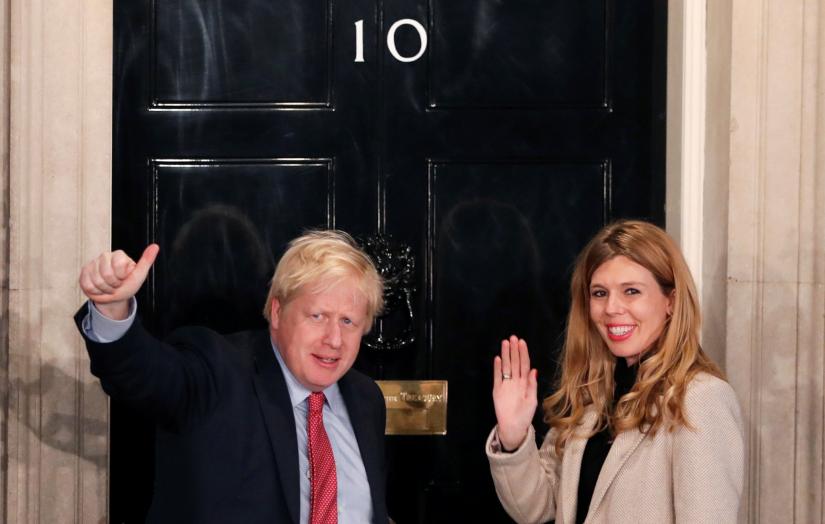 Britain`s Prime Minister Boris Johnson and his girlfriend Carrie Symonds gesture as they arrive at 10 Downing Street on the morning after the general election in London, Britain, December 13, 2019. REUTERS