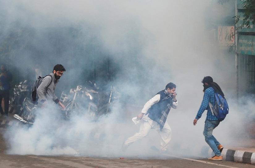 Protesters run for cover amid tear gas fired by police during a protest against the Citizenship Amendment Bill, a bill that seeks to give citizenship to religious minorities persecuted in neighbouring Muslim countries, outside the Jamia Millia Islamia University in New Delhi, India, Dec 13, 2019. REUTERS