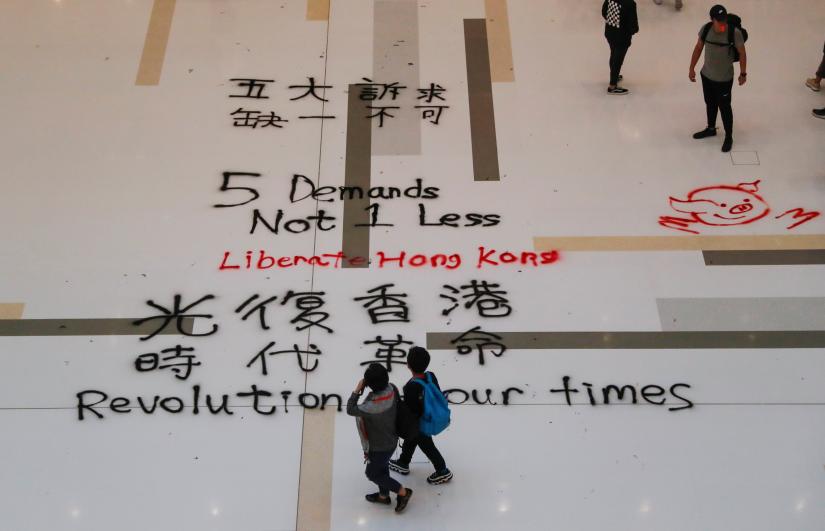 People walk past graffiti slogans written on the floor of a mall, in Hong Kong, China December 15, 2019. REUTERS