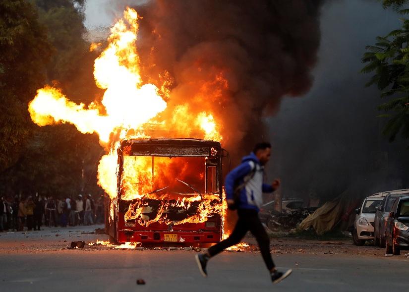 A man runs past a burning bus that was set on fire by demonstrators during a protest against a new citizenship law, in New Delhi, India, Dec 15, 2019. REUTERS