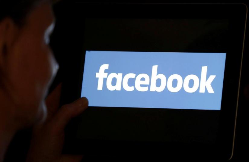 FILE PHOTO: A woman looks at the Facebook logo on an iPad in this photo illustration taken Jun 3, 2018. REUTERS