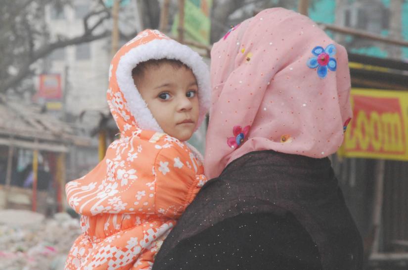 Dressed in winter clothes, a woman is seen holding her baby in Dhaka-Chttagram road on Thursday (Dec 20, 2019). FOCUS BANGLA/File Photo