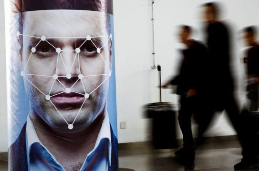 FILE PHOTO:People walk past a poster simulating facial recognition software at the Security China 2018 exhibition on public safety and security in Beijing, China October 24, 2018. REUTERS