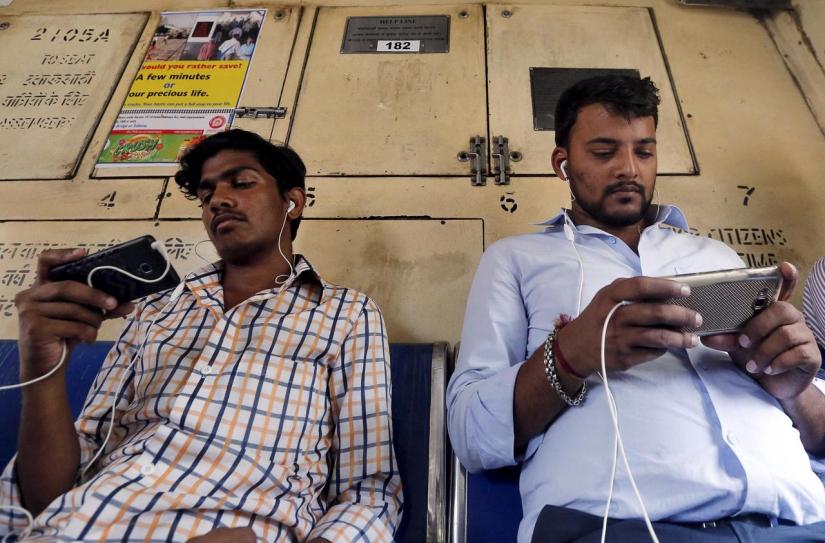 FILE PHOTO: Commuters watch videos on their mobile phones as they travel in a suburban train in Mumbai, India, Apr 2, 2016. REUTERS