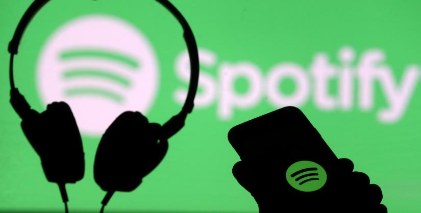 FILE PHOTO: A smartphone and a headset are seen in front of a screen projection of Spotify logo, in this picture illustration taken April 1, 2018. REUTERS