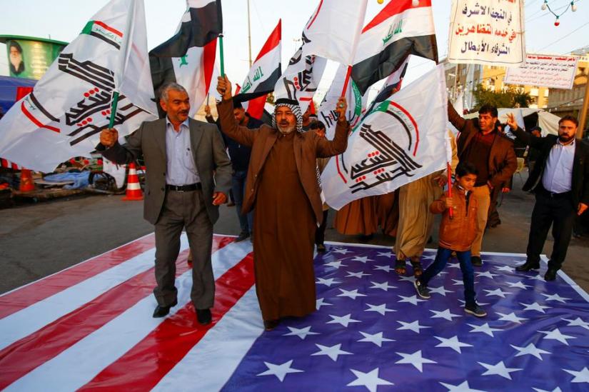 Iraqi people walk on a US flag in a protest after an airstrike at the headquarters of Kataib Hezbollah militia group in Qaim, in the holy city of Najaf, Iraq Dec 30, 2019. REUTERS