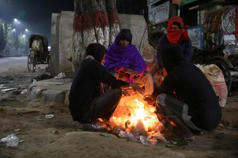 People light a fire in the street to warm themselves up on a winter night in Dhaka, Bangladesh, December 31, 2019. REUTERS