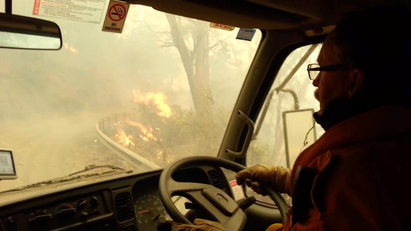 Firefighters drive through flames during evacuation after flames got too large to fight, in Jenolan Caves, New South Wales, Australia December 31, 2019 in this still image taken from social media video. COURTESY RFS via REUTERS
