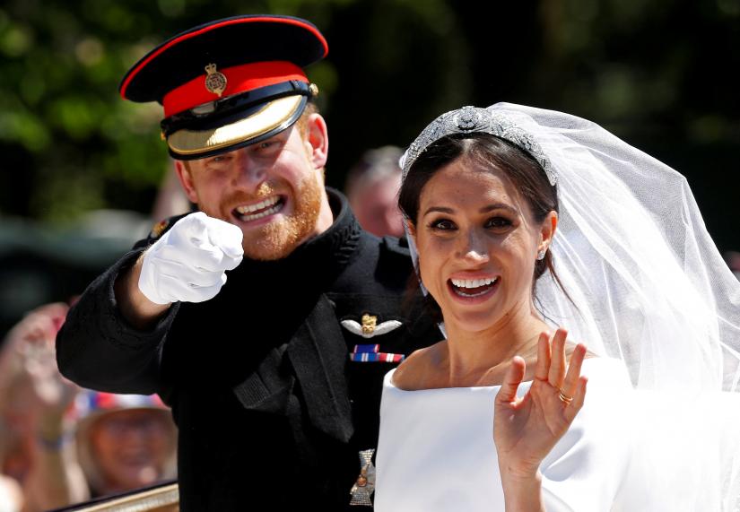 FILE PHOTO: Britain’s Prince Harry gestures next to his wife Meghan as they ride a horse-drawn carriage after their wedding ceremony at St George’s Chapel in Windsor Castle in Windsor, Britain, May 19, 2018. REUTERS